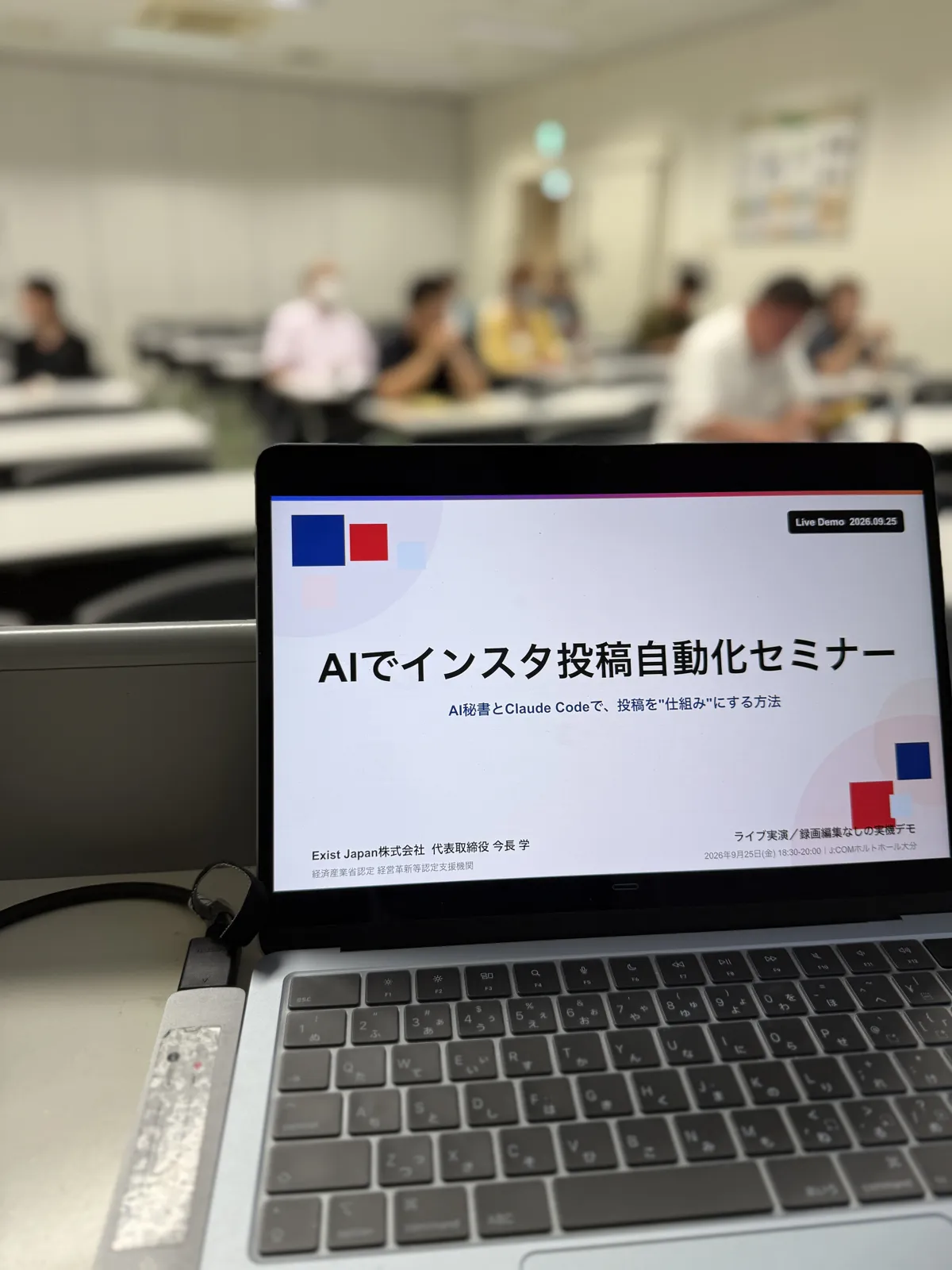 開演前の演台。ノートPCに「AIでインスタ投稿自動化セミナー」のタイトルスライドが映り、奥の客席に参加者が着席しています