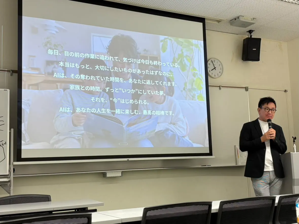 スクリーンに「AIは、その奪われていた時間を、あなたに返してくれます」というメッセージを映し、マイクを持って語る今長学